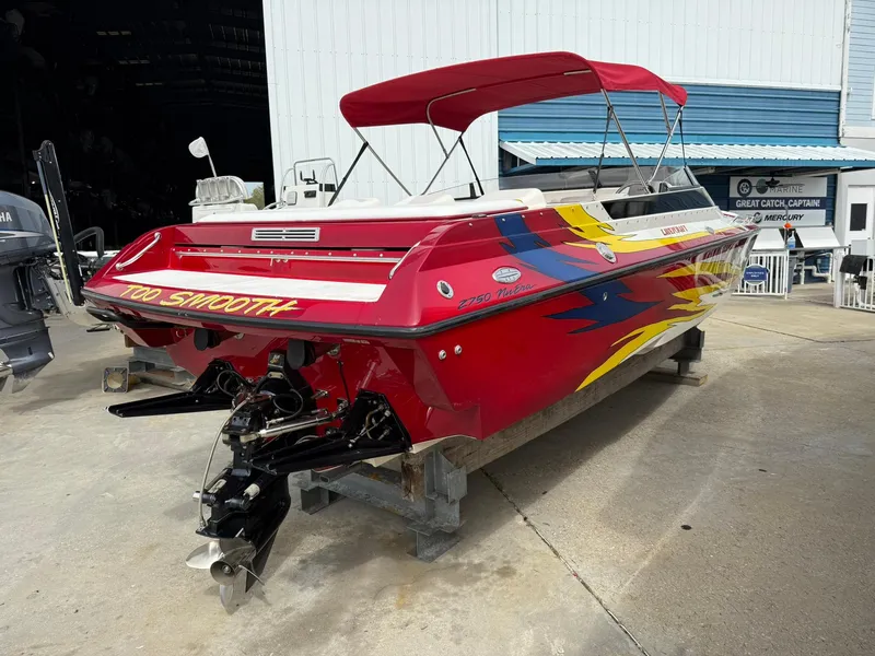 Slide: The Image of 2003 Lavey Craft 2750 NUERA boat with vibrant red and yellow design, docked outdoors. - 2