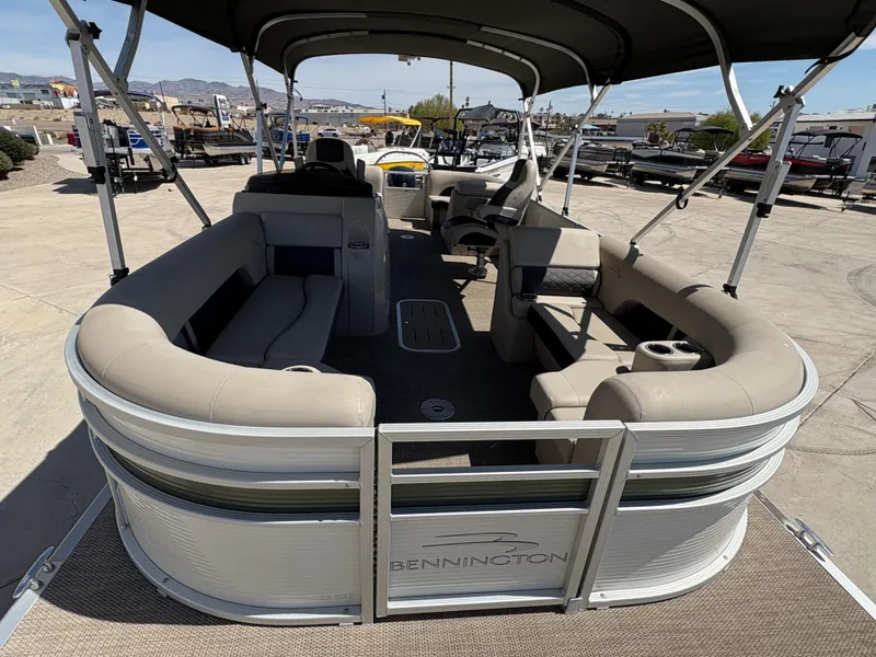Slide: The Image of 2019 Bennington 23 SXP pontoon boat with spacious seating and canopy, docked outdoors. - 4