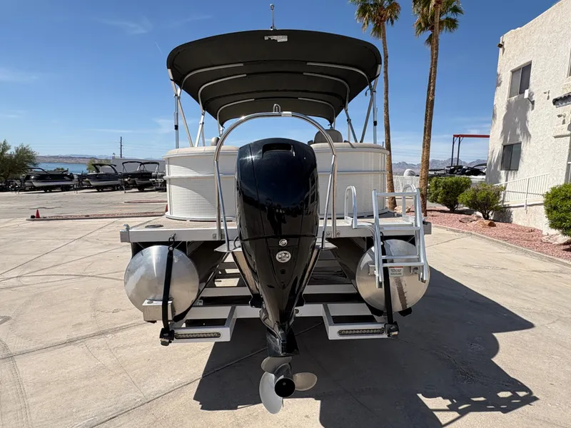 Slide: The Image of 2019 Bennington 23 SXP pontoon boat with canopy, parked outdoors under clear blue sky. - 5