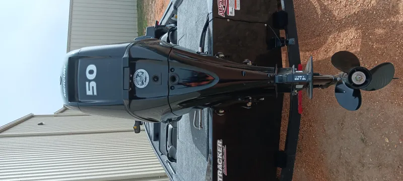 Slide: The Image of 2025 Tracker Bass Tracker Classic XL with 50 HP outboard motor, parked on gravel. - 16