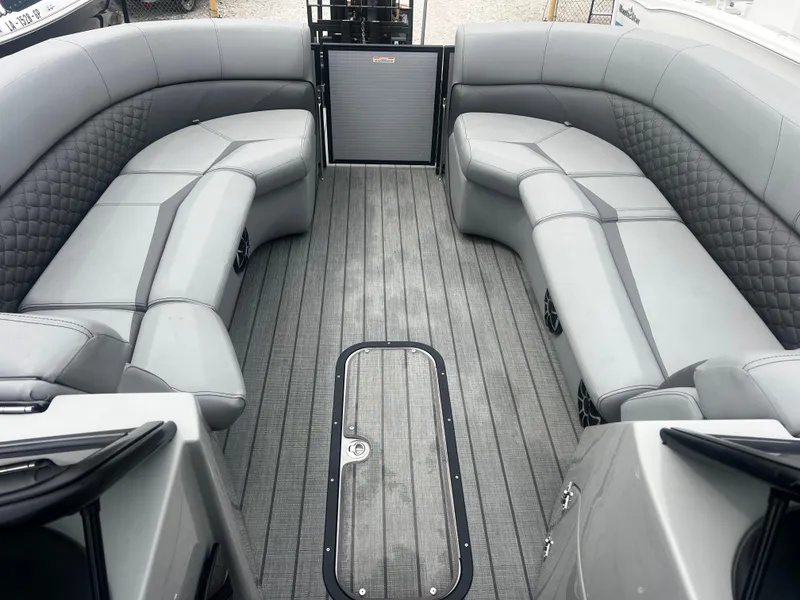 Slide: The Image of 2022 Manitou 27 boat interior with gray seating and flooring, featuring spacious layout. - 4