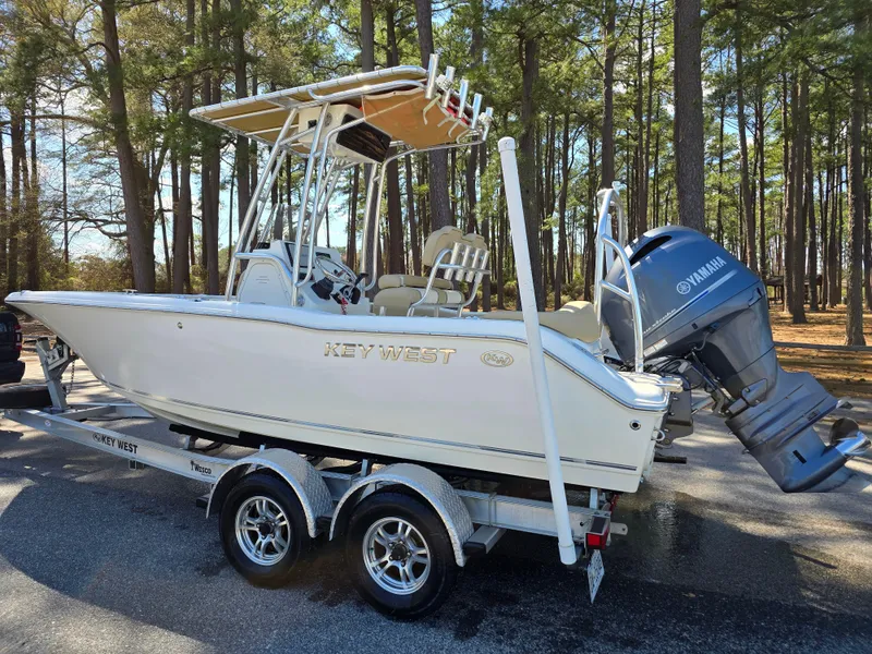 Slide: The Image of 2019 Key West 203 FS boat on trailer with Yamaha outboard motor, parked in wooded area. - 0