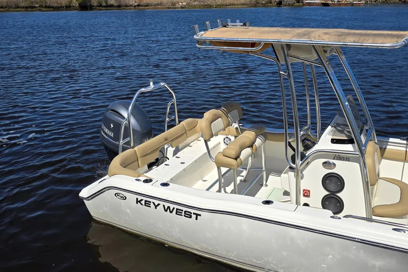 Slide: The Image of 2019 Key West 203 FS boat on calm water, featuring beige seating and a Yamaha outboard motor. - 12