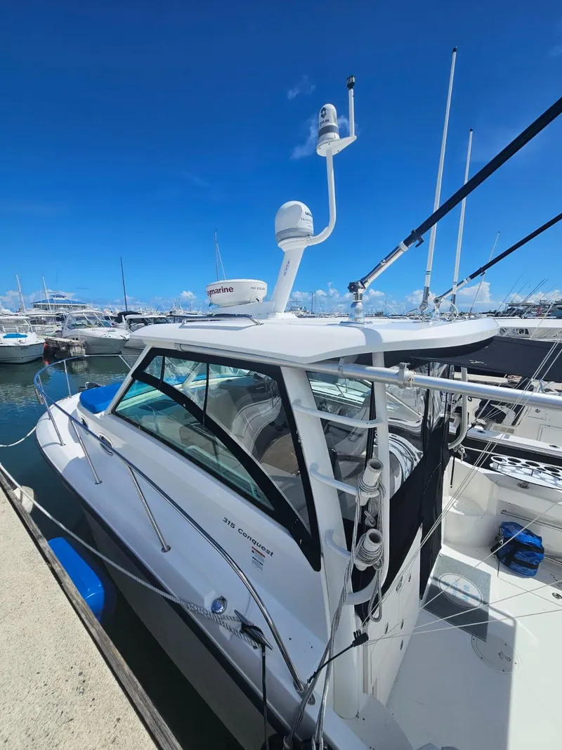 Slide: The Image of 2013 Boston Whaler 315 Conquest boat docked in a marina under clear blue skies. - 10
