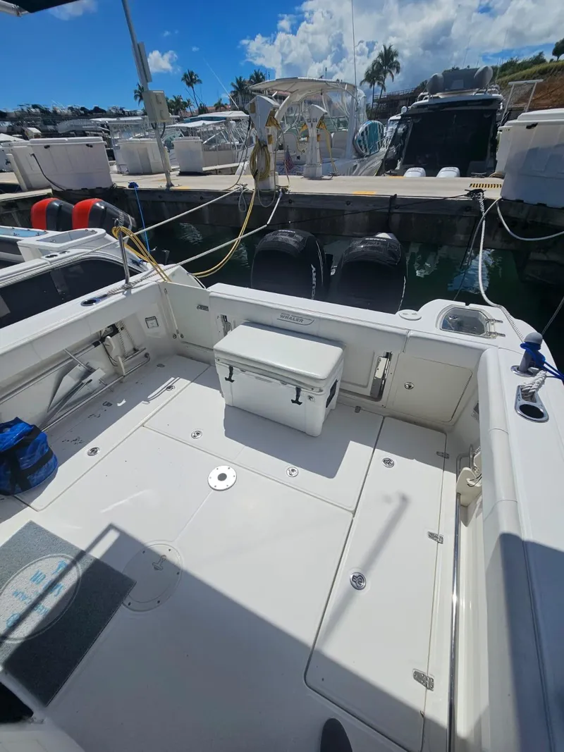 Slide: The Image of 2013 Boston Whaler 315 Conquest boat docked, featuring spacious deck and cooler. - 12