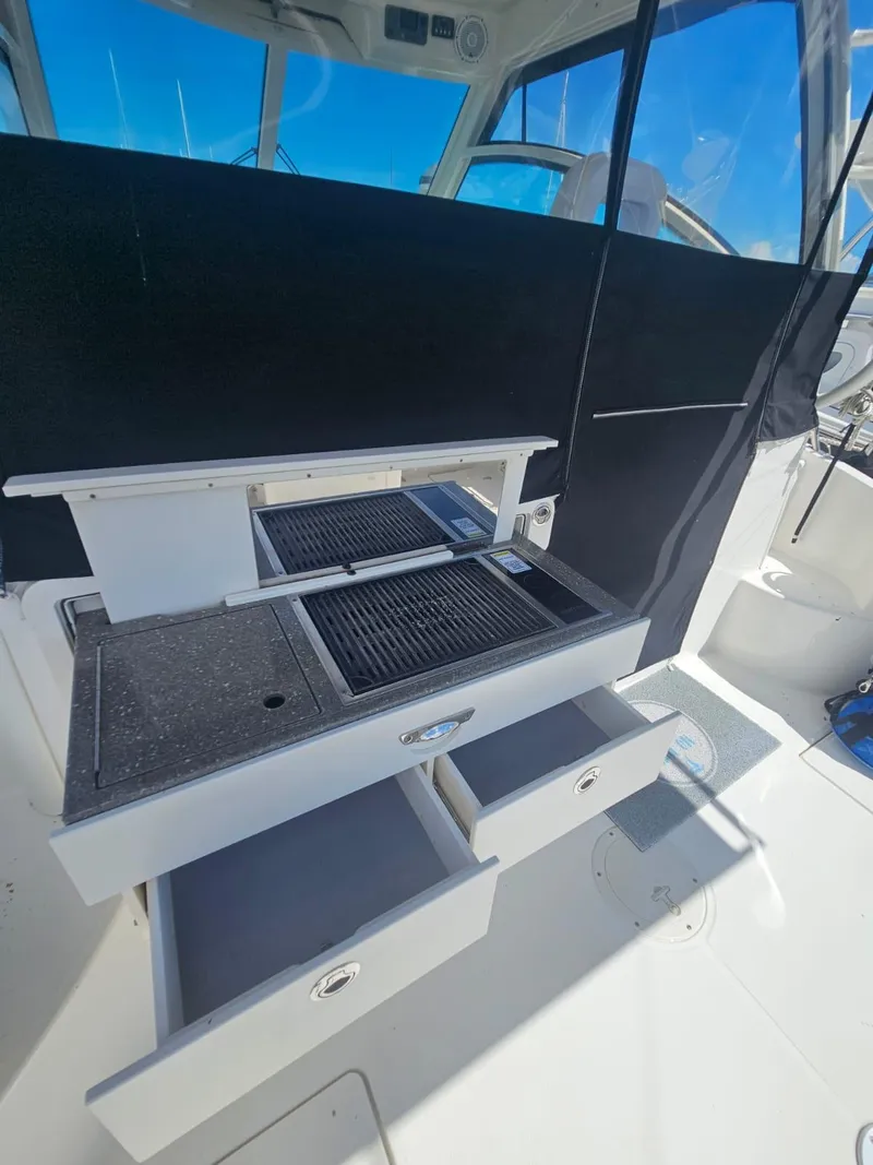 Slide: The Image of 2013 Boston Whaler 315 Conquest boat interior with open storage drawers and grill. - 21