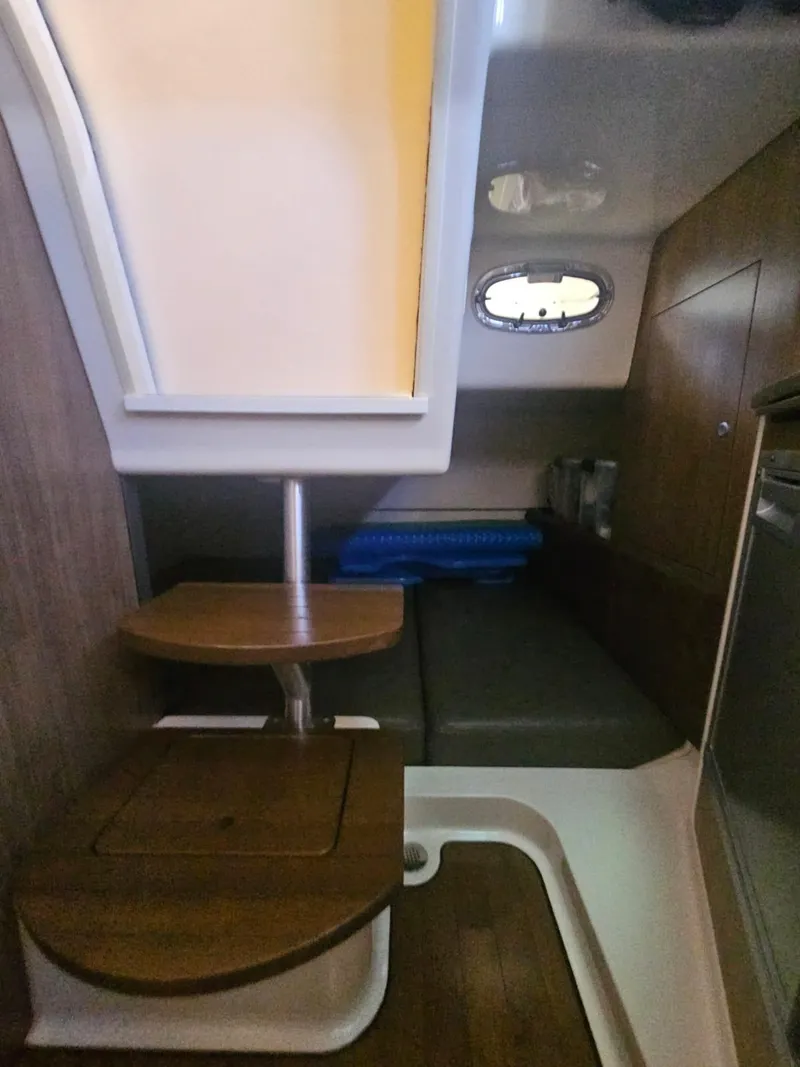 Slide: The Image of 2013 Boston Whaler 315 Conquest cabin interior with wooden steps and seating area. - 4