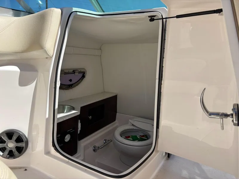Slide: The Image of 2018 Regal 26 OBX boat interior with compact bathroom, featuring a toilet and sink. - 14