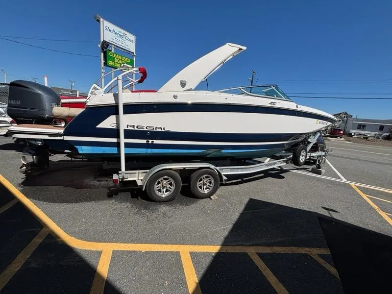 Slide: The Image of 2018 Regal 26 OBX boat on trailer in parking lot under clear blue sky. - 2