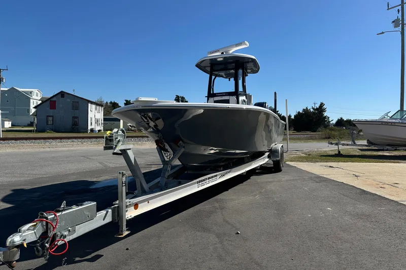 Slide: The Image of 2023 Tidewater 2700 Carolina Bay boat on trailer, parked outdoors under clear blue sky. - 2