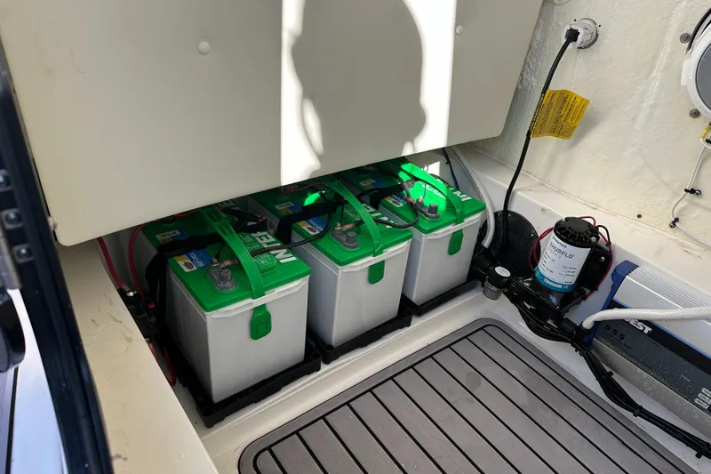 Slide: The Image of Battery compartment of 2023 Tidewater 2700 Carolina Bay boat, featuring three green batteries. - 51