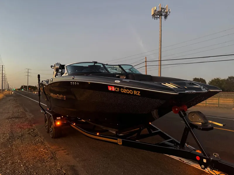 Slide: The Image of 2018 MasterCraft XStar boat on trailer, parked roadside at sunset. - 2
