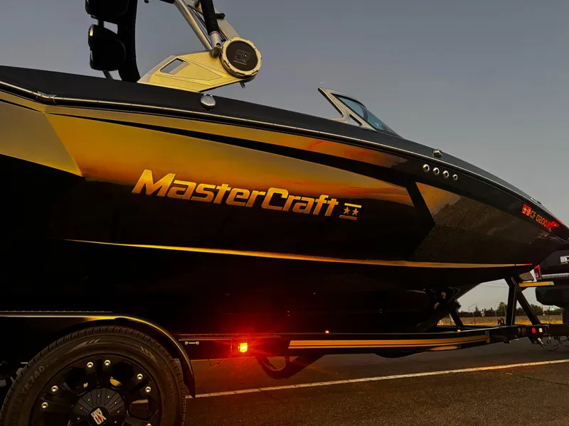Slide: The Image of 2018 MasterCraft XStar boat on trailer at sunset, showcasing sleek design and branding. - 3