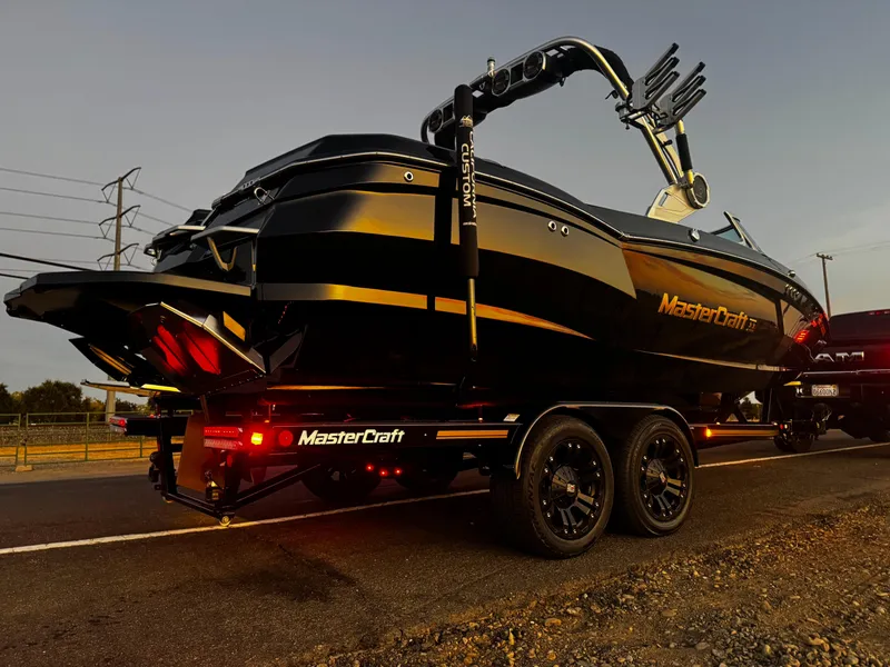 Slide: The Image of 2018 MasterCraft XStar boat on trailer at sunset, showcasing sleek design and modern features. - 4