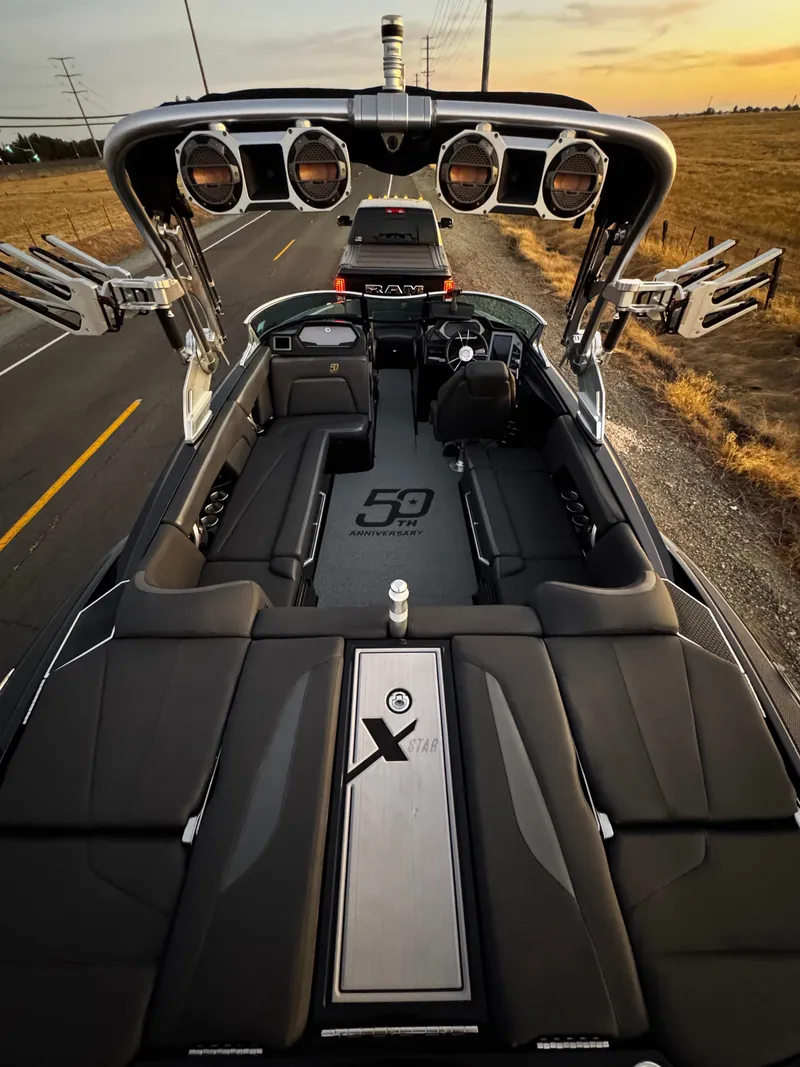 Slide: The Image of 2018 MasterCraft XStar boat on trailer, sleek design, parked on roadside at sunset. - 7