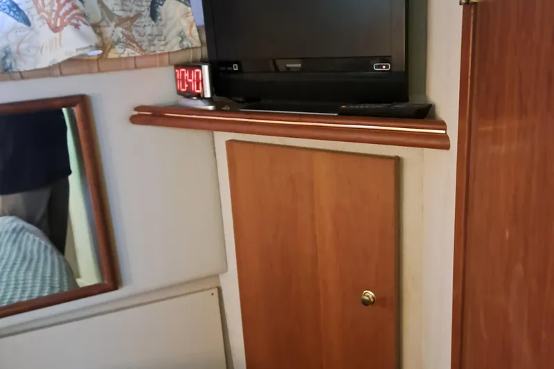 Slide: The Image of 1999 Cruisers aft cabin interior with TV, clock, and wooden cabinet. - 11