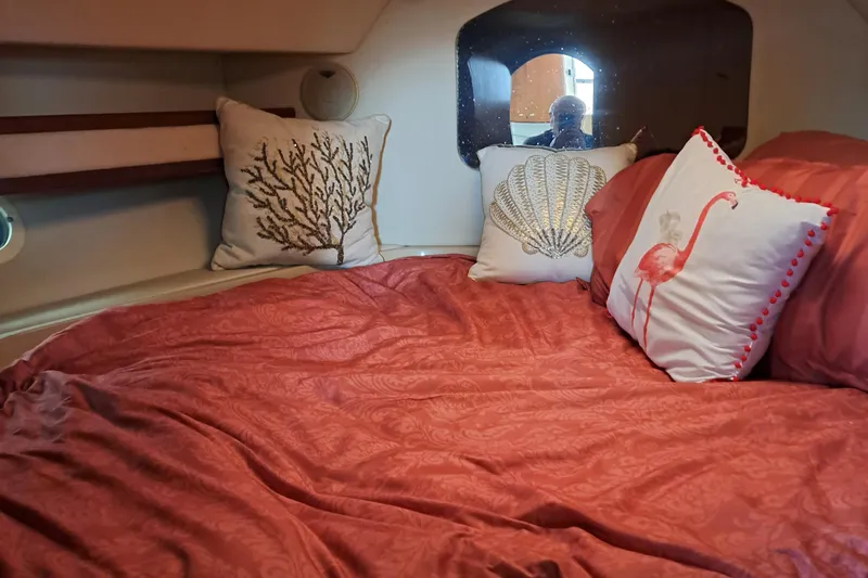 Slide: The Image of 1999 Cruisers aft cabin with cozy bed, coral-themed pillows, and red bedding. - 15