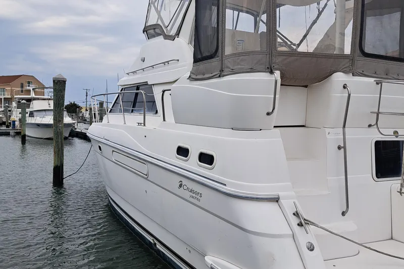 Slide: The Image of 1999 Cruisers aft cabin yacht docked in marina, featuring sleek white design and spacious upper deck. - 9