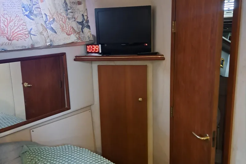 Slide: The Image of 1999 Cruisers aft cabin interior with TV, clock, and wooden door. - 12