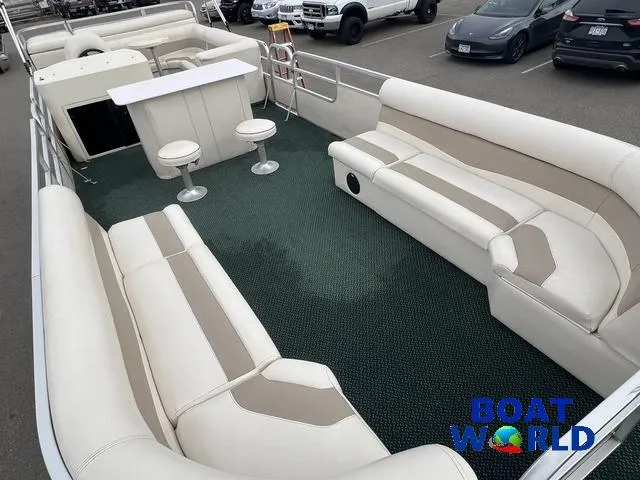 Slide: The Image of Spacious 2000 Weeres Sundeck 280 pontoon boat with seating and table, parked in a lot. - 14