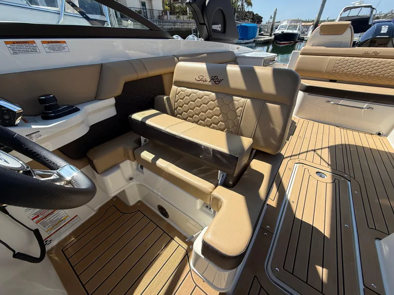 Slide: The Image of 2022 Sea Ray 290 SDX OB boat interior with tan seating and wood-style flooring. - 16