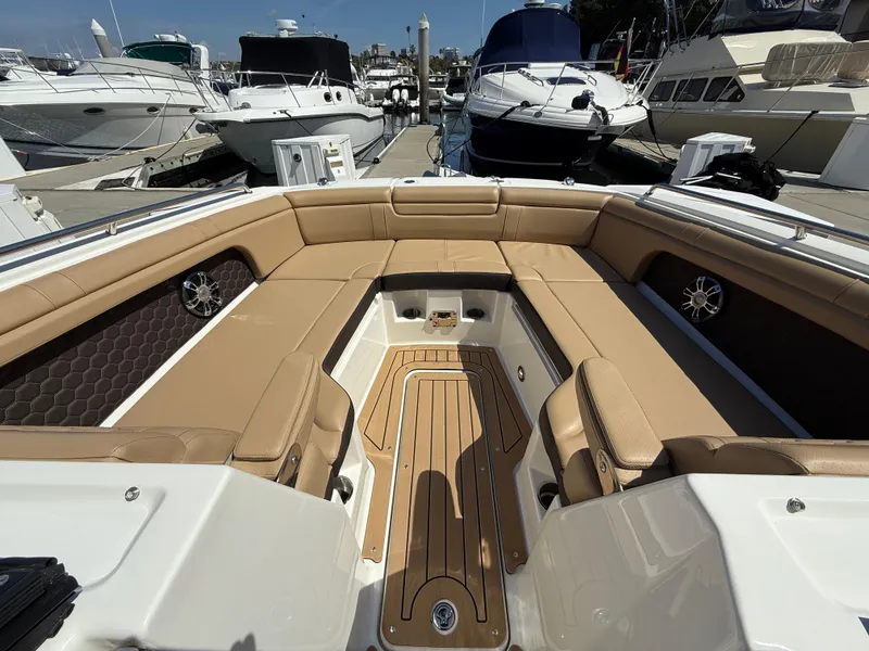 Slide: The Image of 2022 Sea Ray 290 SDX OB boat interior with tan seating and wood flooring at a marina. - 21