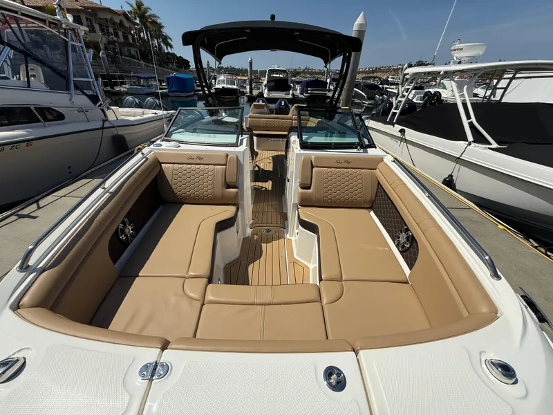 Slide: The Image of 2022 Sea Ray 290 SDX OB boat with spacious tan seating and sleek design at a marina. - 23