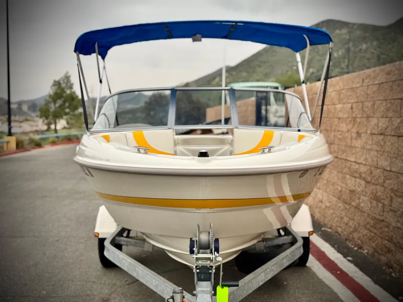 Slide: The Image of 2005 Maxum 1800 SR3 boat with blue canopy on trailer, parked near mountains. - 2