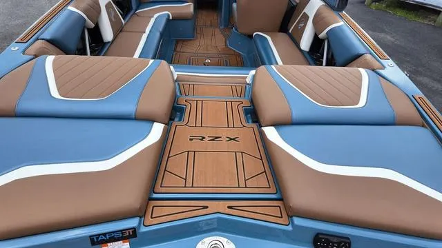 Slide: The Image of 2021 Tigé RZX Class 22 boat interior with blue and brown seating. - 12