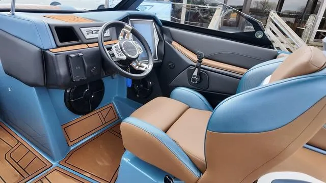 Slide: The Image of 2021 Tigé RZX Class 22 RZX boat interior with blue and tan seating, modern dashboard. - 17