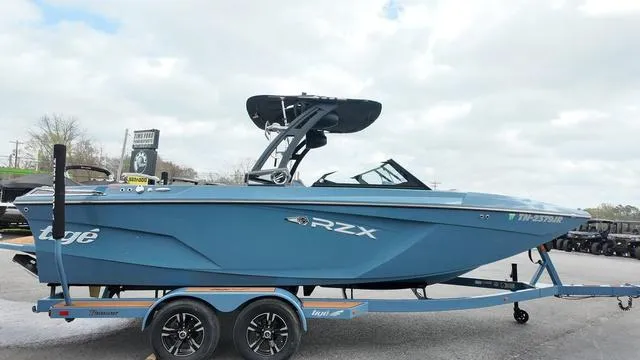 Slide: The Image of 2021 Tigé RZX Class 22 RZX boat on trailer, blue exterior, parked outdoors. - 3