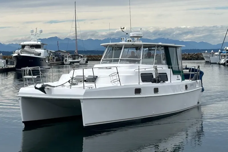 The Image of 2002 Endeavour Trawlercat 36 in marina, calm waters, mountains in background. - 0
