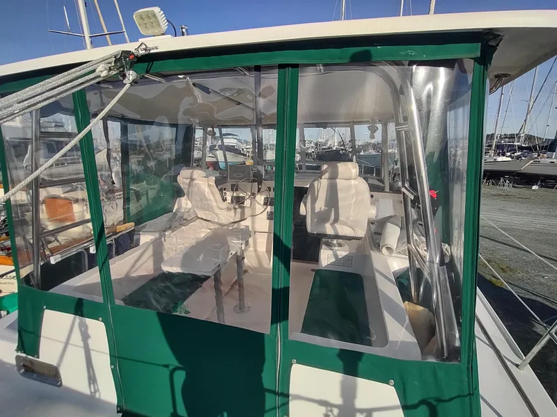 Slide: The Image of 2002 Endeavour Trawlercat 36 cockpit with green canopy and seating, docked at marina. - 18