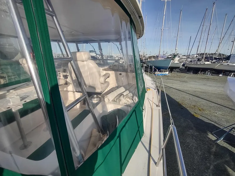 Slide: The Image of 2002 Endeavour Trawlercat 36 with green canopy, docked at a marina with sailboats. - 19