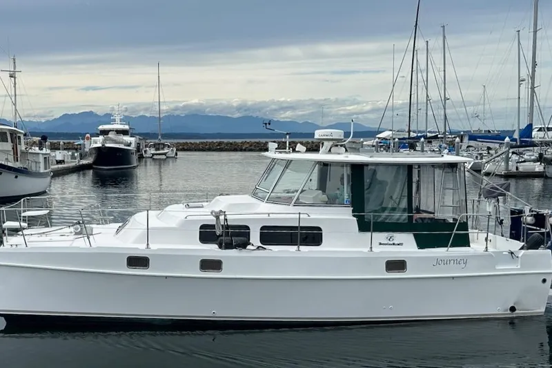 Slide: The Image of 2002 Endeavour Trawlercat 36 docked in a marina with mountains in the background. - 4