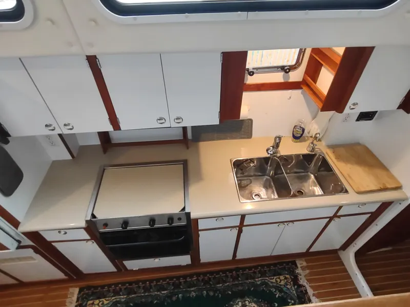 Slide: The Image of Kitchen area of 2002 Endeavour Trawlercat 36 with stove, sink, and wooden cabinetry. - 49