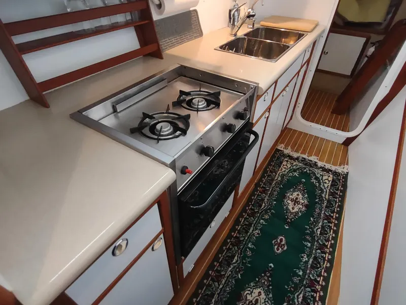 Slide: The Image of 2002 Endeavour Trawlercat 36 kitchen with stove, sink, and elegant rug. - 51