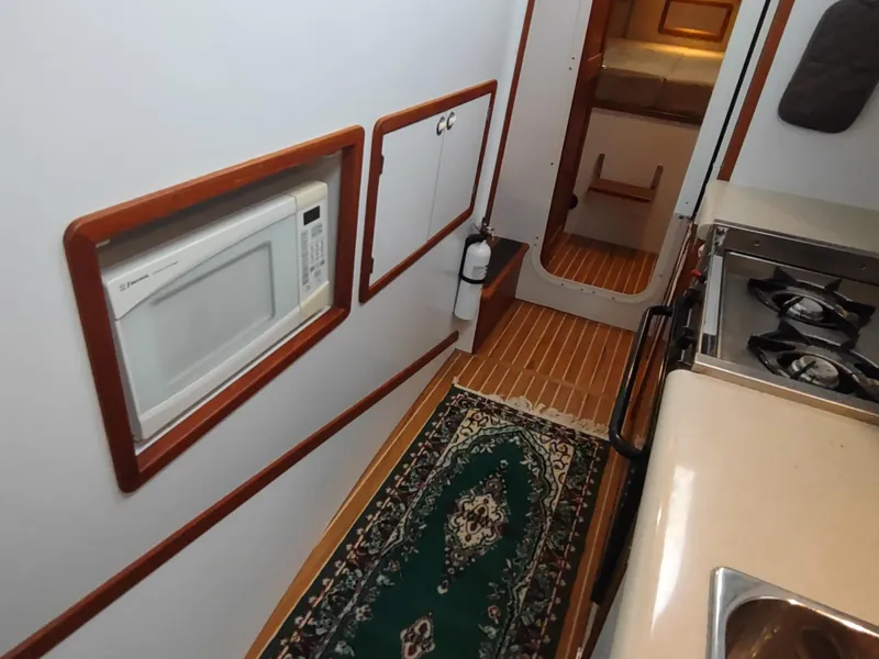 Slide: The Image of 2002 Endeavour Trawlercat 36 interior kitchen with microwave, stove, and green rug. - 54