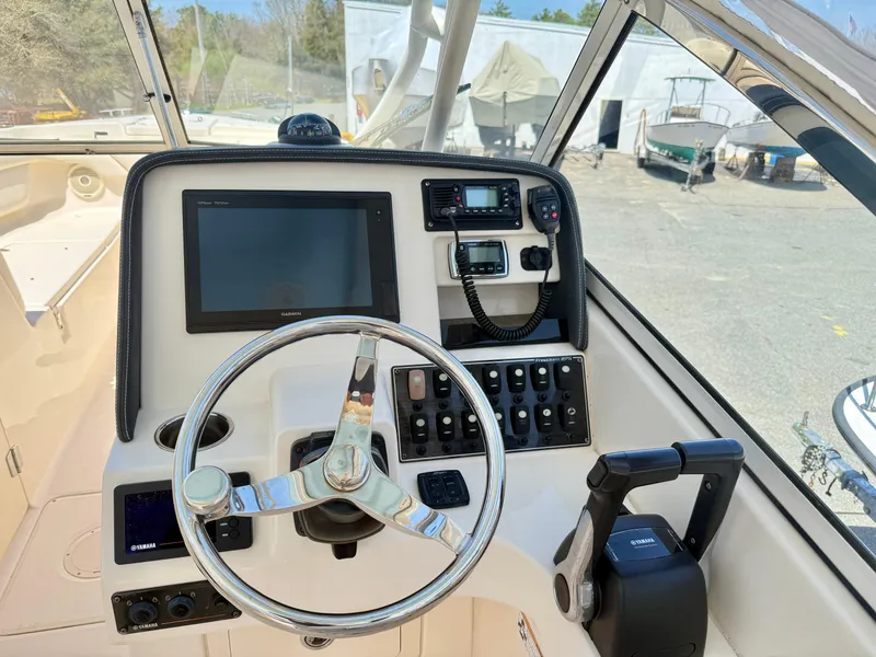 Slide: The Image of 2017 Grady-White Freedom 275 boat dashboard with steering wheel and navigation controls. - 6