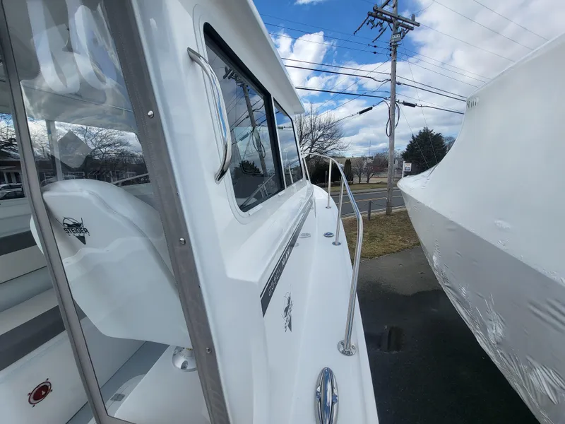 Slide: The Image of 2025 Steiger Craft 255 DV MIAMI boat exterior with clear sky and road in background. - 25