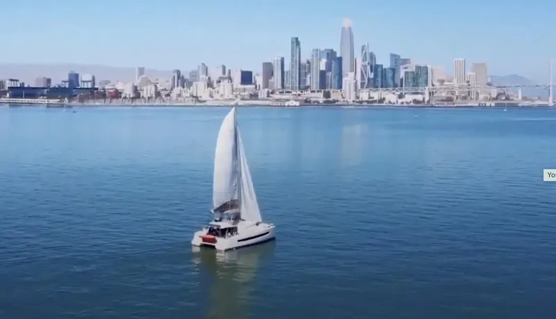 Slide: The Image of Sailboat Bali 4.8 (2021) cruising near a city skyline on a clear day. - 1
