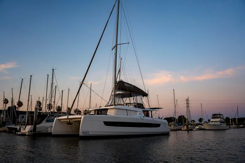 Slide: The Image of 2021 Bali 4.8 catamaran docked at sunset in a serene marina setting. - 17