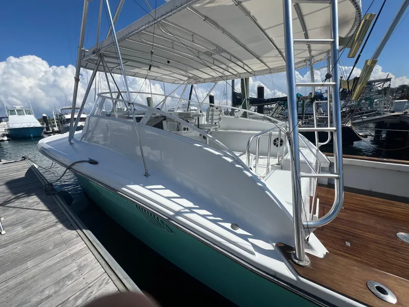 Slide: The Image of 1997 Strike 42 boat docked, featuring sleek design and spacious deck under a canopy. - 16