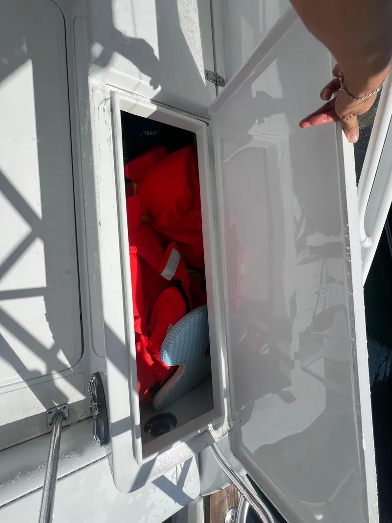 Slide: The Image of Open storage compartment on a 1997 Strike 42 boat, revealing red life jackets inside. - 30
