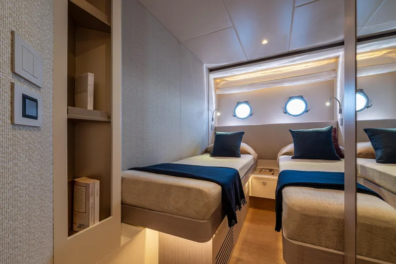 Slide: The Image of Luxurious twin cabin interior on 2026 Absolute 62' Navetta yacht, featuring elegant bedding and porthole windows. - 26