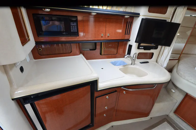 Slide: The Image of 2002 Sea Ray 340 Sundancer interior kitchen with sink, microwave, and TV. - 15