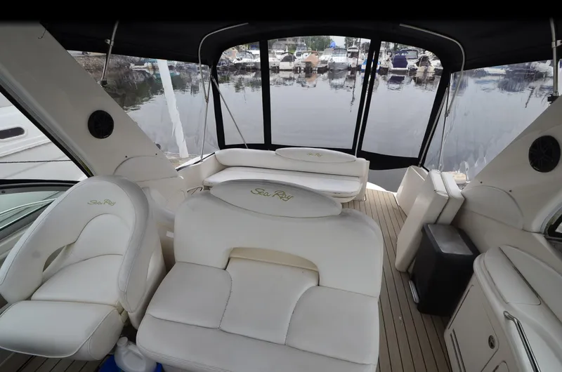 Slide: The Image of 2002 Sea Ray 340 Sundancer interior with white seating and marina view. - 5