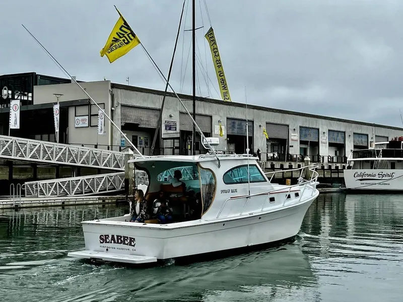Slide: The Image of 1999 Mainship Pilot 30 boat named "Seabee" cruising in a marina with overcast skies. - 1