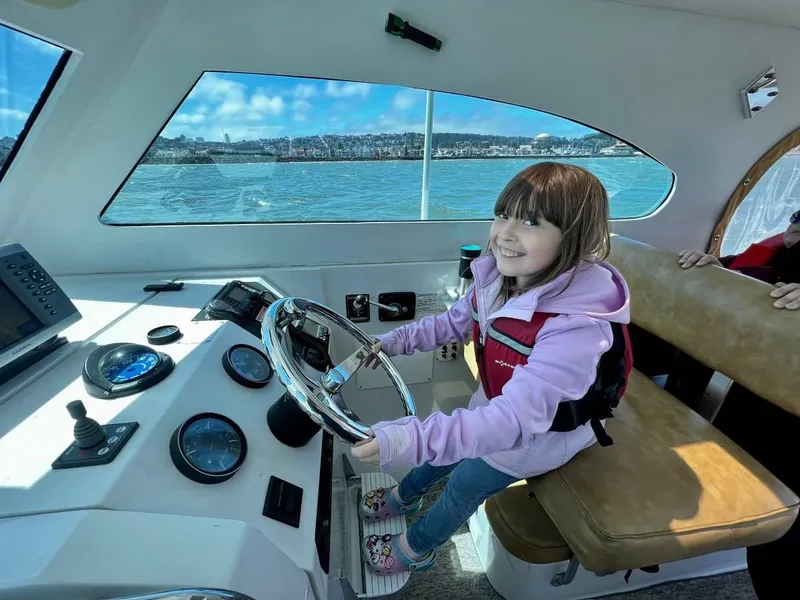 Slide: The Image of Young girl steering a 1999 Mainship Pilot 30 boat on a sunny day. - 14