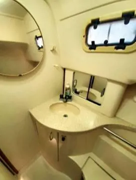 Slide: The Image of 1999 Mainship Pilot 30 boat bathroom with sink, mirror, and porthole window. - 4